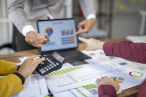 Group of people looking at a laptop with a calculator.