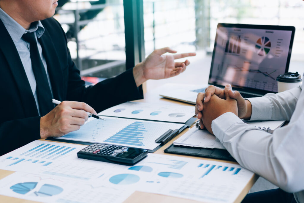 Male manager is explaining about the company's cost graph on the laptop computer for employees to listen to and share the analysis together.